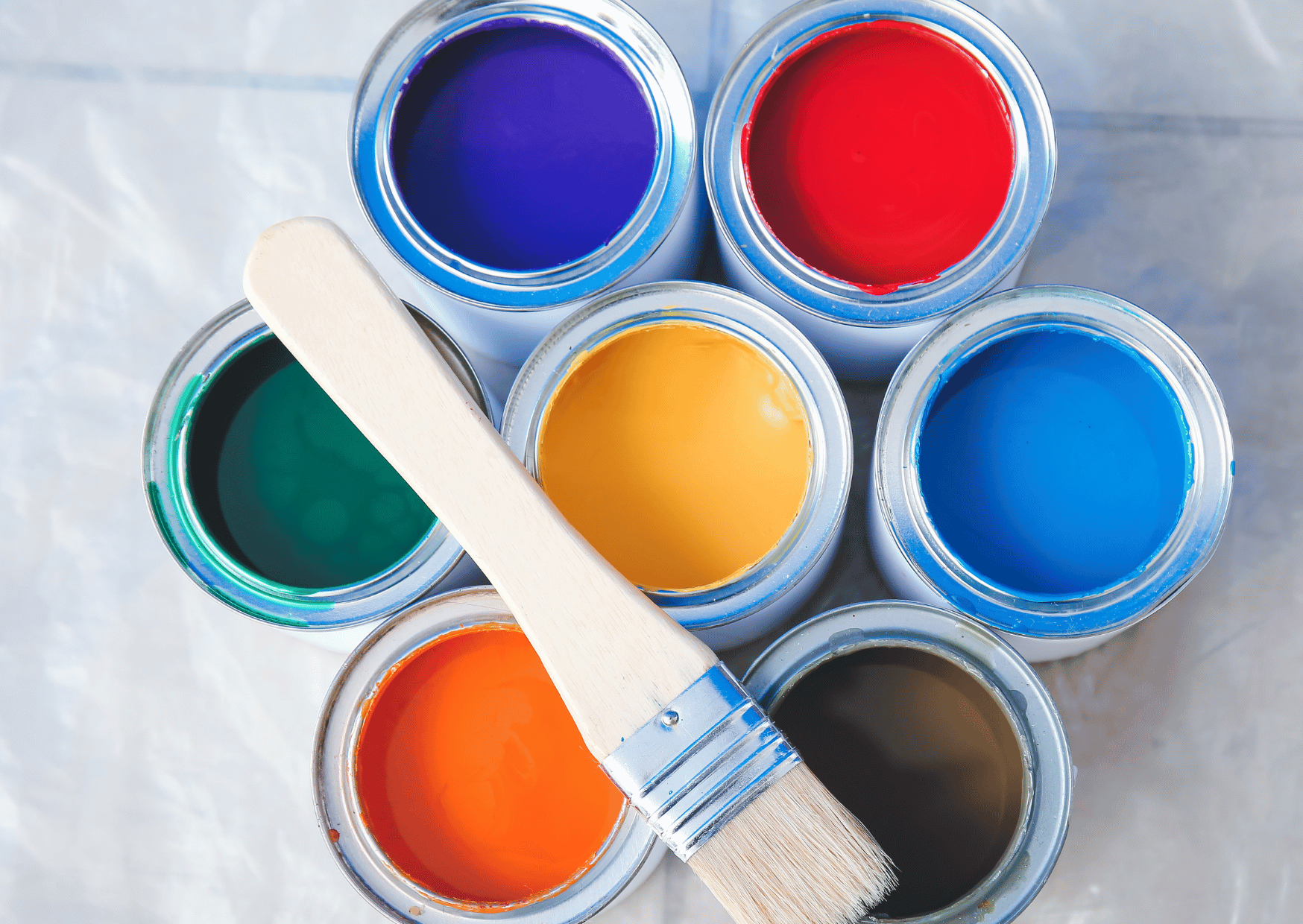 different coloured paint tins withs a small brush