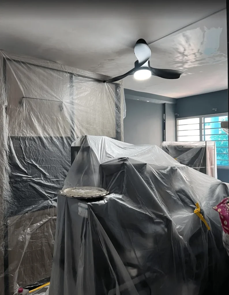 Living room furniture covered in plastic sheeting before painting