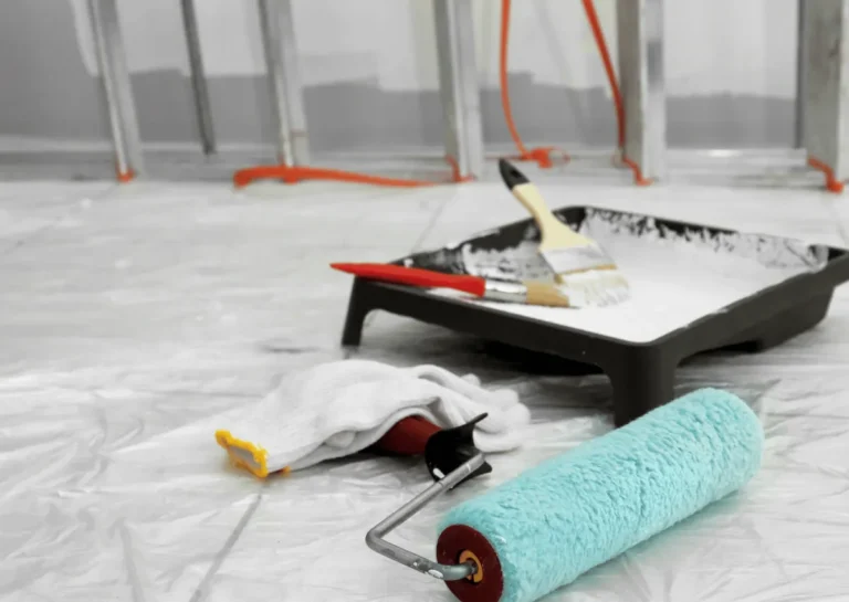 Paint tray, brush and roller on a protective plastic sheet
